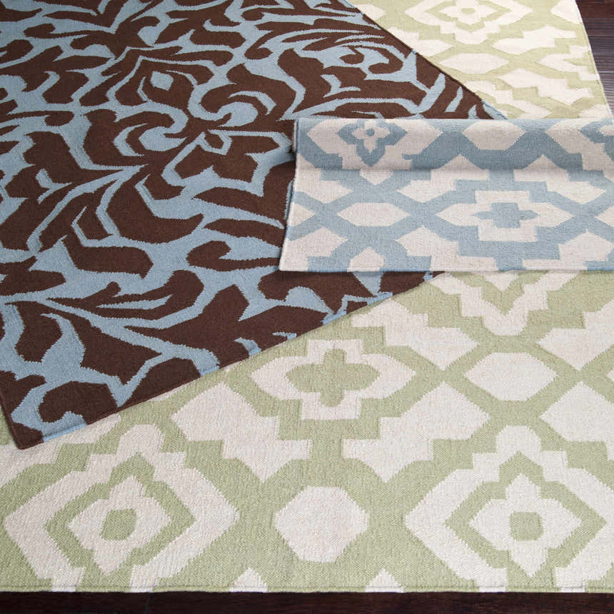 Close-up of Oppelo Area Rug showing dark brown and sage geometric patterns, hand woven wool texture. Styleshot