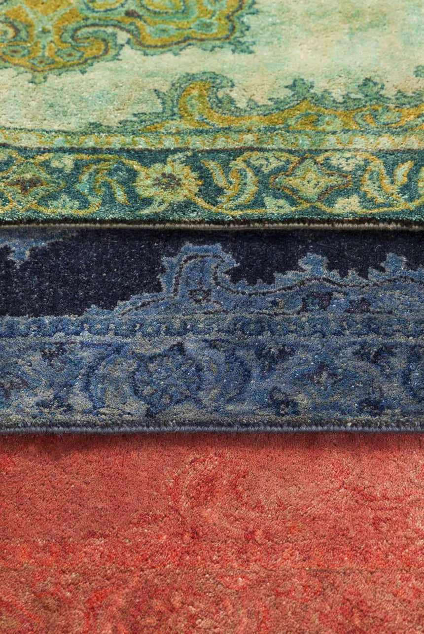 Close-up of the hand-tufted Gilbertsville Area Rug. Features a traditional pattern in dusty sage, teal, and red wool. Styleshot