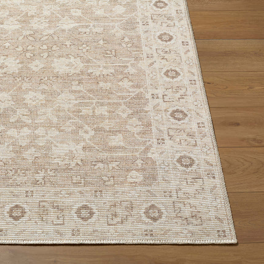 Close-up of the Asha Machine Woven Nabela Noor rug. Features a traditional pattern in dark brown, mustard, off-white, and taupe. Front