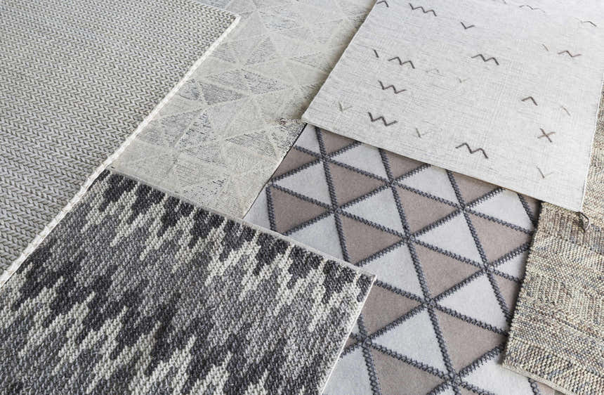 Close-up of various cream-colored Christoval Area Rug samples with geometric, striped, and textured designs. Styleshot