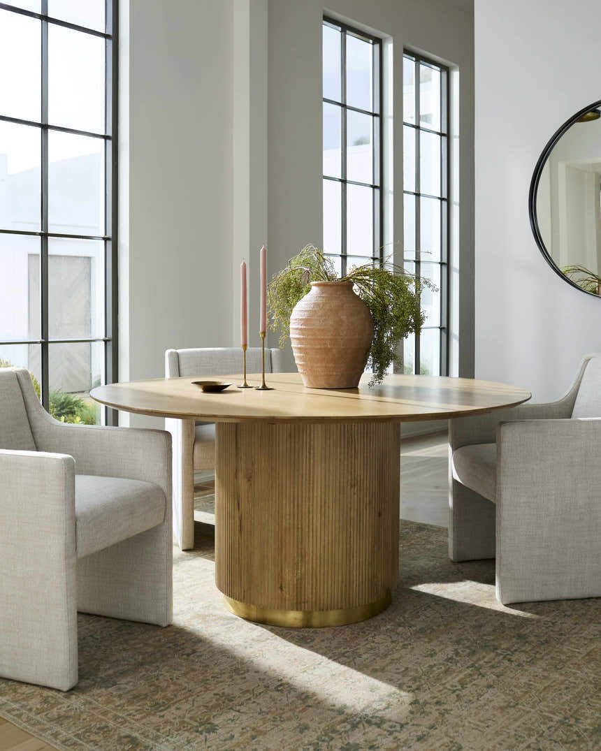 Dining room scene with a Becki Owens x Livabliss Renaissance Area Rug in beige, olive, and tan under a round table and modern chairs. Styleshot