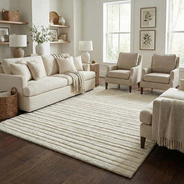 Living room scene with a beige Edolie Washable Area Rug, cream sofa, armchairs, and dark wood floors. Neutral, cozy aesthetic. Roomscene-Rectangle