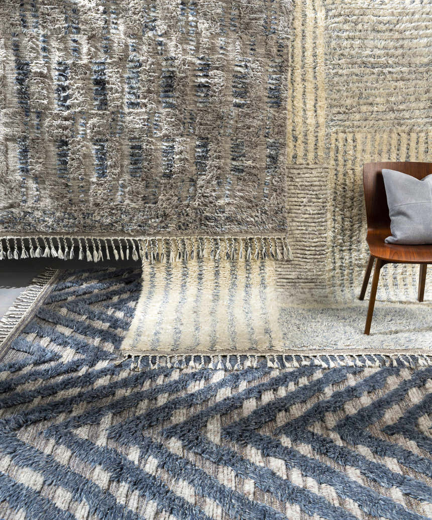 Close-up of textured Plean Premium Rug in charcoal, cream, and denim with a geometric pattern and knotted fringe. Styleshot