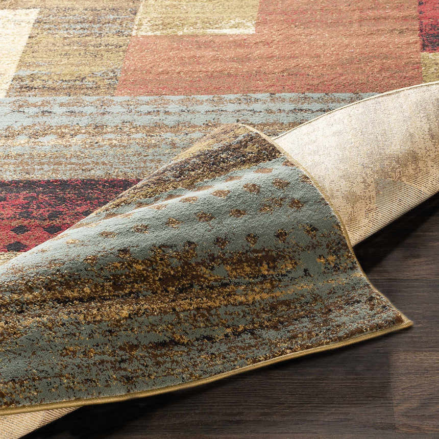 Close-up of the Sentinel Riley Geometric Rug showing the geometric pattern, colors, and rug backing. Fold