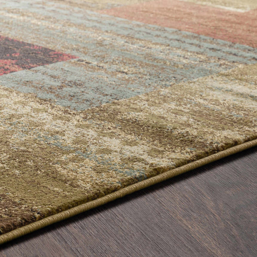 Close-up of the Sentinel Riley Geometric Rug, showing its texture, geometric pattern, and colors like green, brown, red, and blue. Texture
