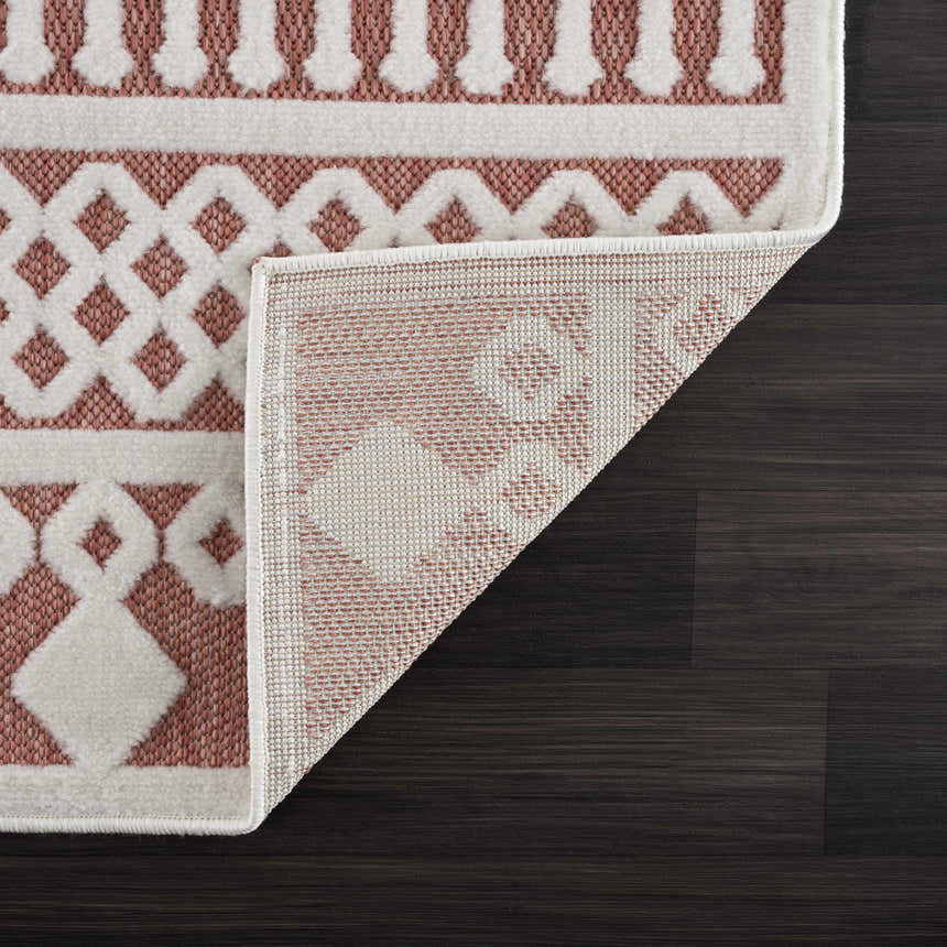 Close-up of Jove Orange Outdoor Rug showing bone and terracotta geometric pattern and machine woven construction. Fold