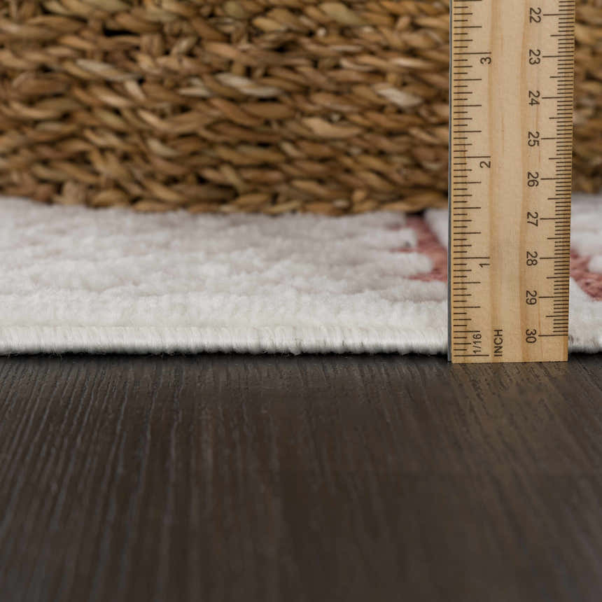 Close-up of the Jove Orange Outdoor Rug showing the pile height with a ruler, plus bone and clay colors. Pile