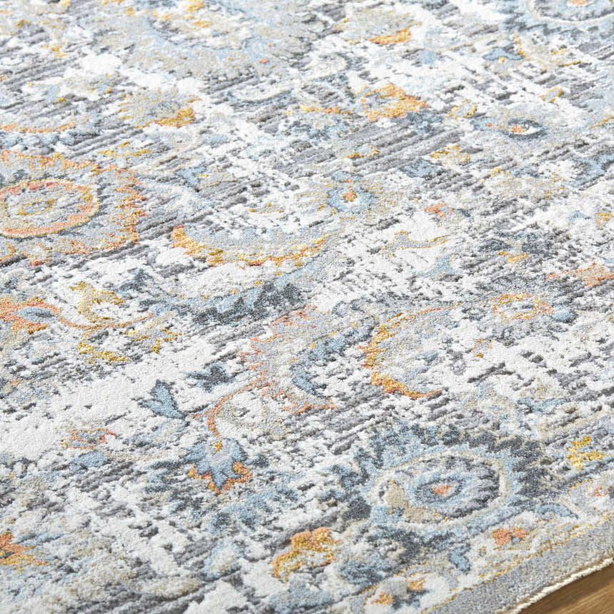 Close-up of the Atara Area Rug showing its traditional gray, blue, and gold floral pattern and soft, textured pile. Texture