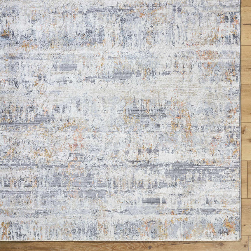 Close-up of the Guoda Area Rug, a contemporary design in driftwood, gray, and nutmeg hues. Machine woven texture. Corner