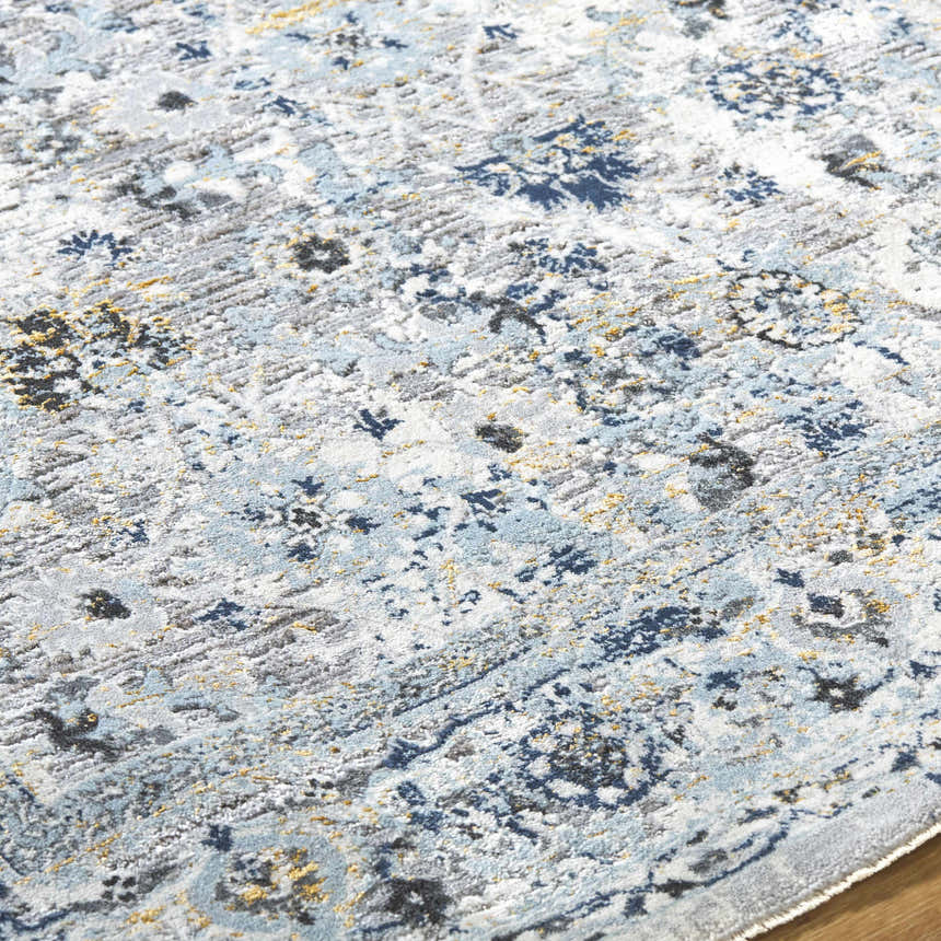 Close-up of the Irida Area Rug, featuring a traditional pattern in dark gray, denim, and light gray hues. Texture