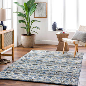 Living room scene with a blue and off-white geometric Shou Area Carpet, wood furniture, and a large potted plant. Roomscene-Rectangle