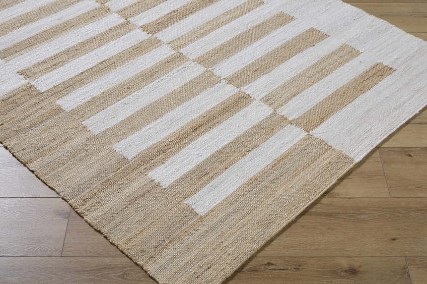 Close-up of the hand-woven Soren Area Rug. Jute rug features a geometric stripe pattern in ash, light silver, and tan. Corner