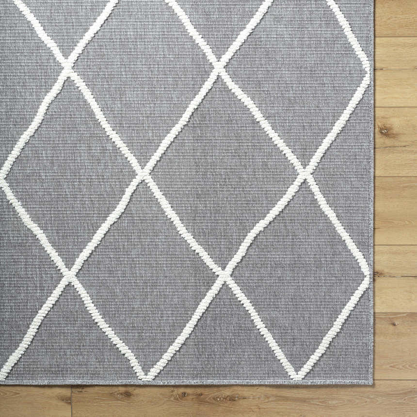 Close-up of Amani Gray Washable Rug with white geometric diamond pattern on a wood floor. Contemporary, farmhouse style. Corner