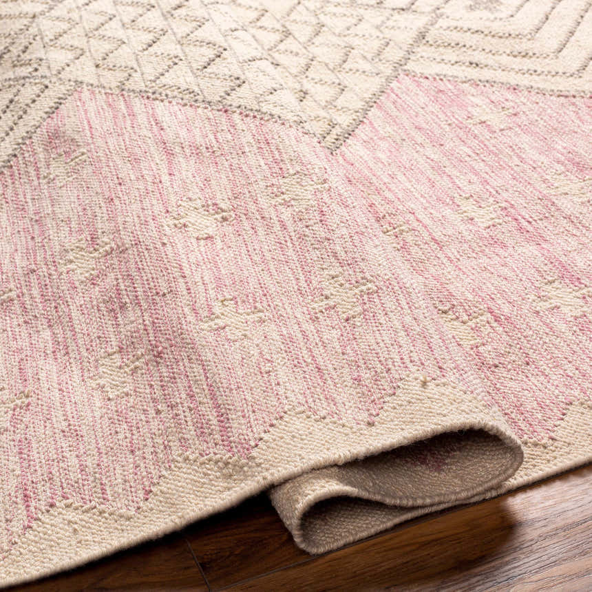 Close-up of the hand woven Sang Area Rug. Tan and dark pink hues with a geometric pattern. Recycled PET yarn texture. Fold