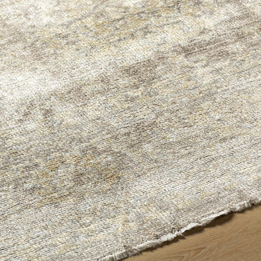 Close-up of the hand-knotted Stirum Area Rug. Light gray, taupe, and wheat tones with a subtle texture. Viscose rug on wood floor. Texture