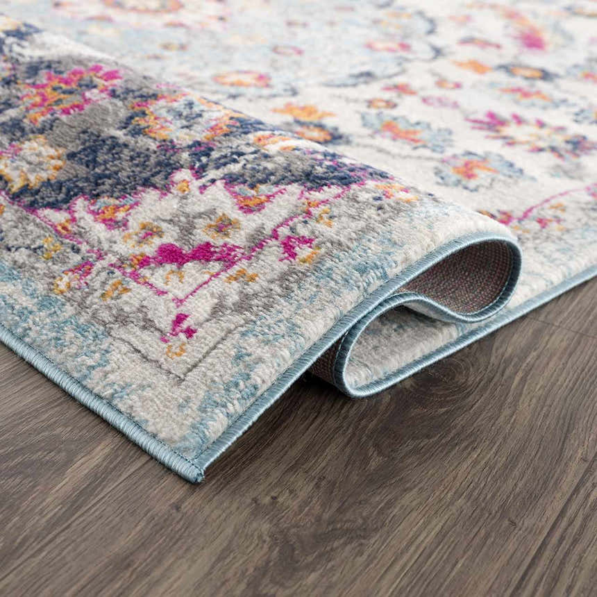 Close up of the Tigril Blue 2303 Area Rug showing beige, ivory, turquoise, pink, and navy floral pattern and texture. Fold