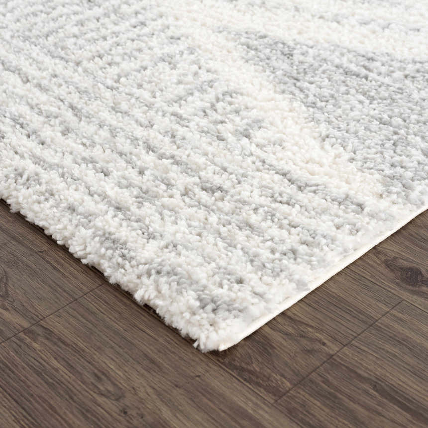 Close-up of the Trunding Plush Area Rug in Gray, showing its soft, shaggy texture and geometric pattern on a wood floor. Corner