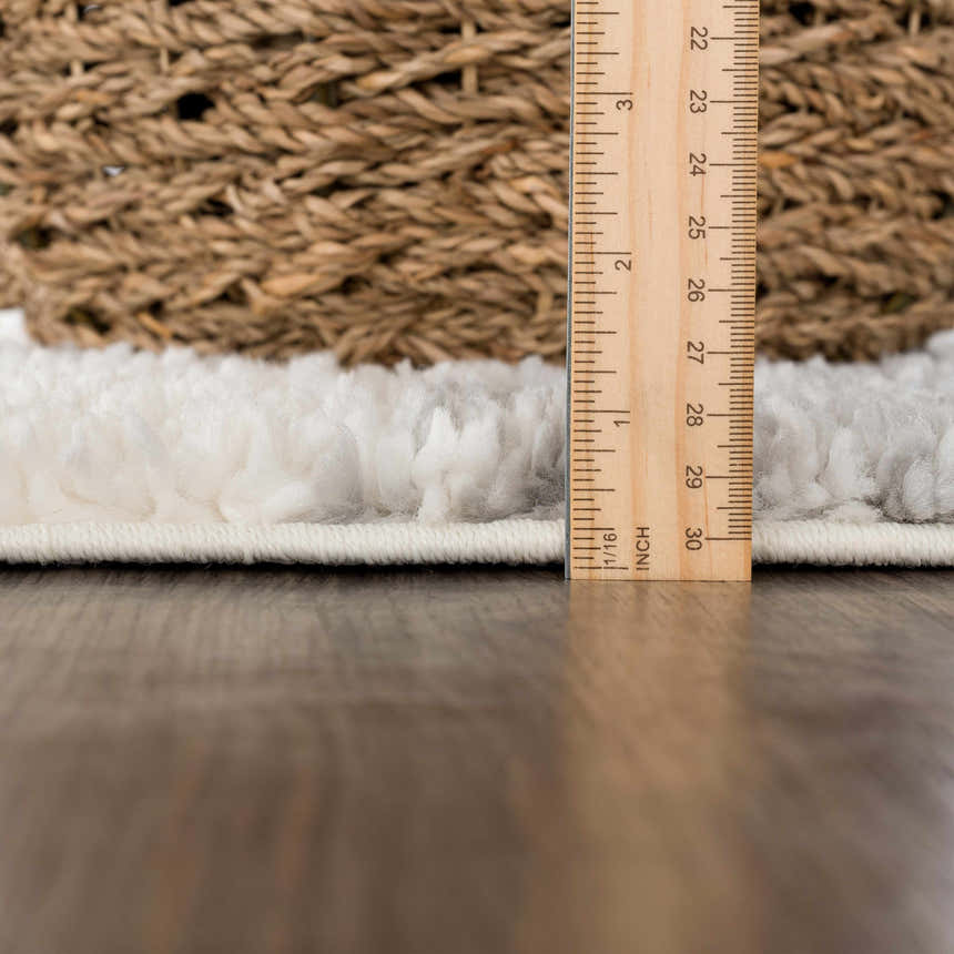 Close-up of the plush Trunding rug in gray showing the pile height with a ruler and the rug's edge. Pile