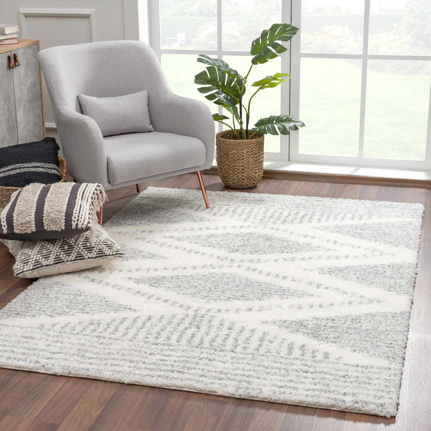 Cozy living room scene with a gray armchair and the Trunding Plush Area Rug in Gray with a geometric pattern. Roomscene-Rectangle
