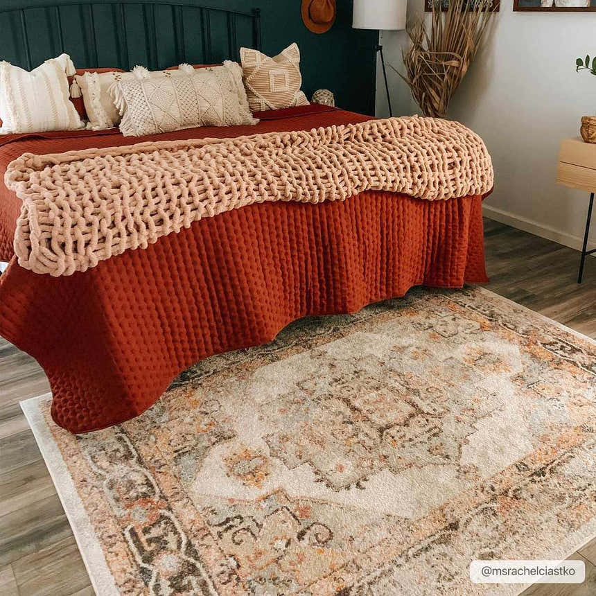 Bedroom scene with a beige and rust Hillcrest Area Rug under a bed with rust bedding and neutral pillows. Roomscene-Rectangle