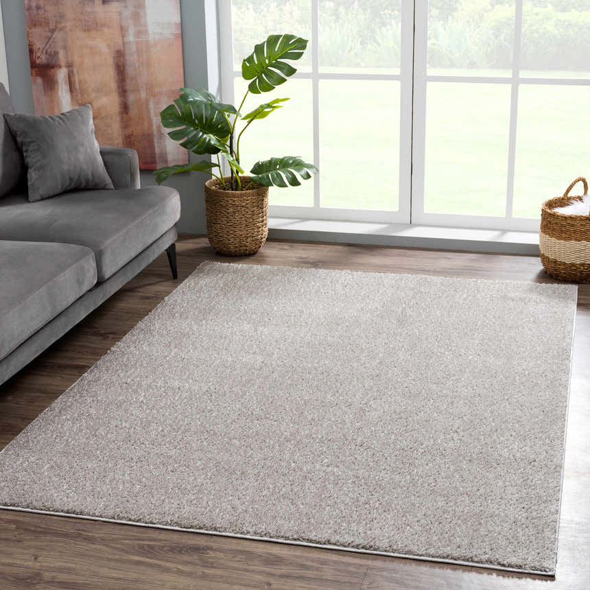 Living room scene with a gray sofa and Judy Solid Gray Washable Shag Rug on a wood floor near a bright window. Roomscene-Rectangle