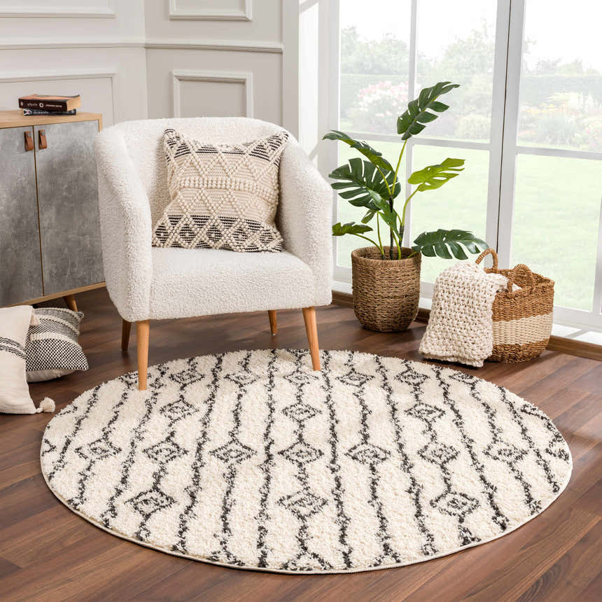 Living room scene with a round, shag Bayanga Area Rug in charcoal and ivory, styled with a cozy armchair. Roomscene-Round