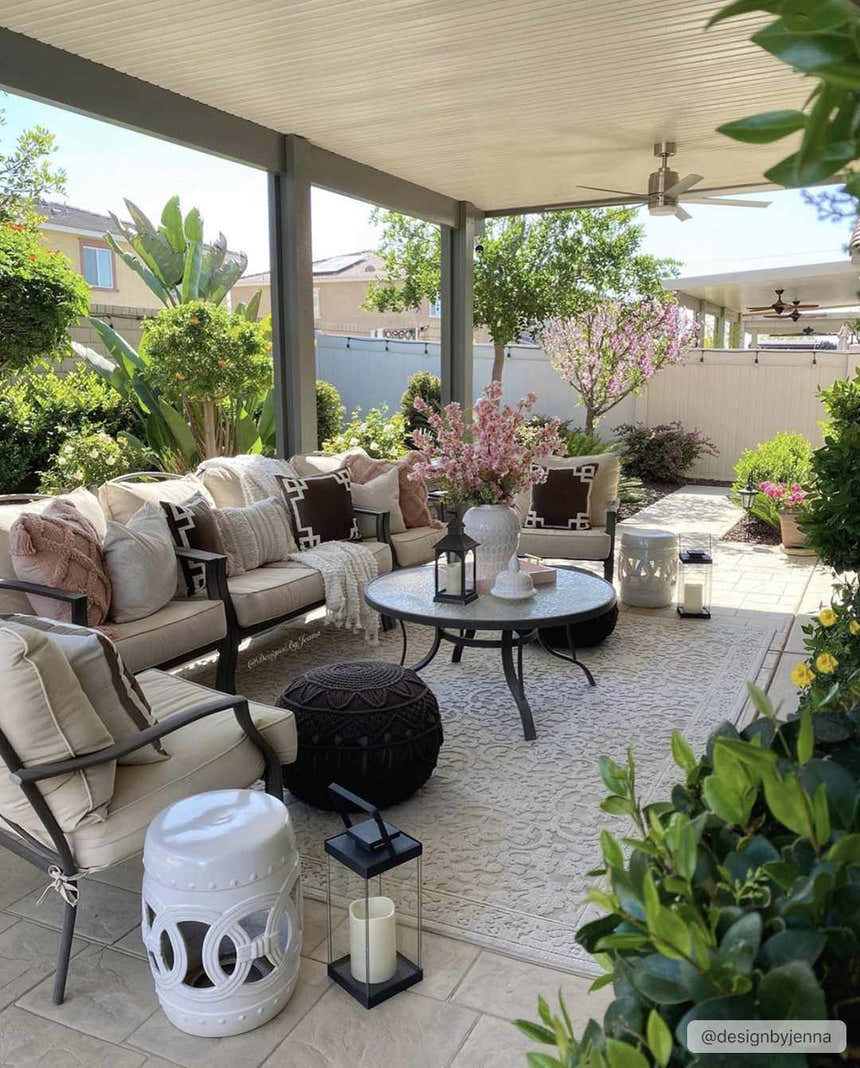 Outdoor patio with beige Innaloo 3D rug, seating area, round table, lanterns, and lush greenery. Roomscene-Rectangle