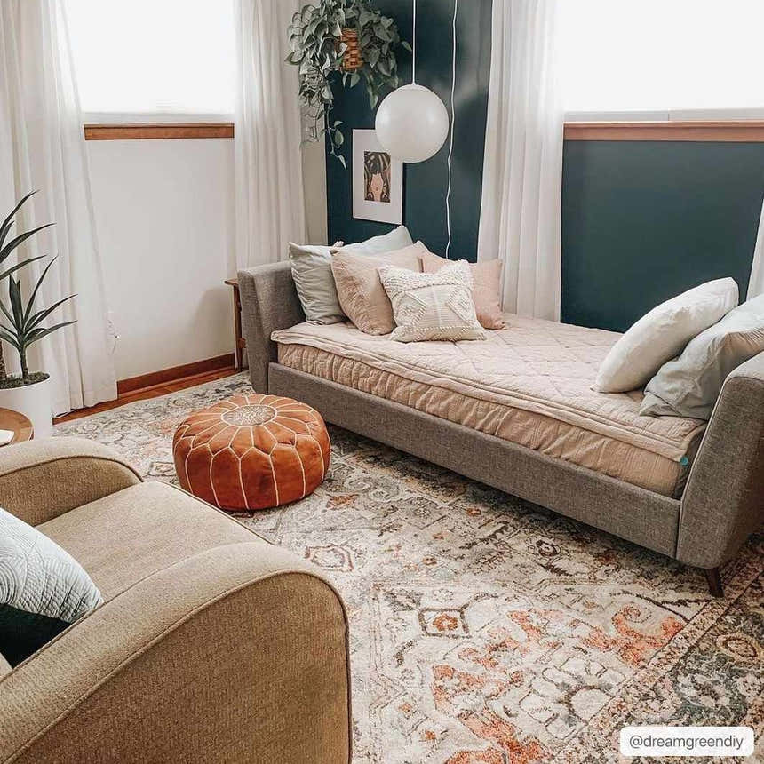 Cozy living room scene with a brick red and camel Bolinas Area Rug, daybed, tan chair, and leather pouf. Roomscene-Rectangle