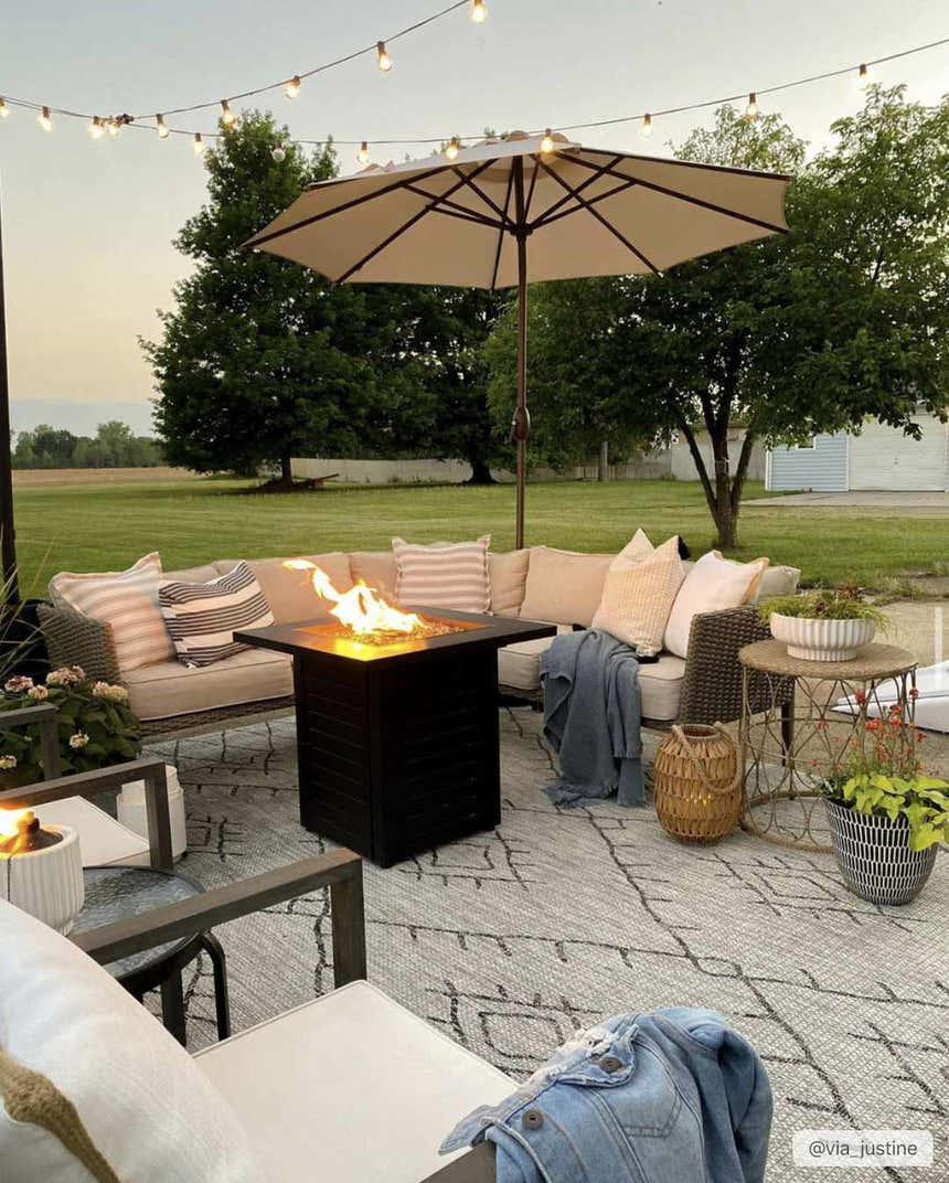 Outdoor patio with fire pit on a Marwood Nordic Performance Rug, surrounded by seating and string lights. Styleshot