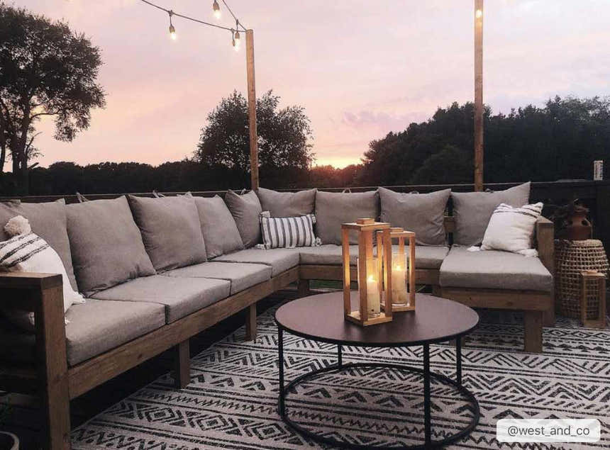 Outdoor patio scene with gray cushioned sectional on the black and white Catrine Indoor Outdoor Rug. Roomscene-Rectangle