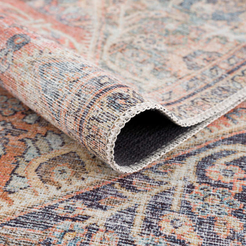 Close-up of rolled Konstantina Washable Area Rug showing Persian-style design in aqua, beige, brown, and dark blue. Fold