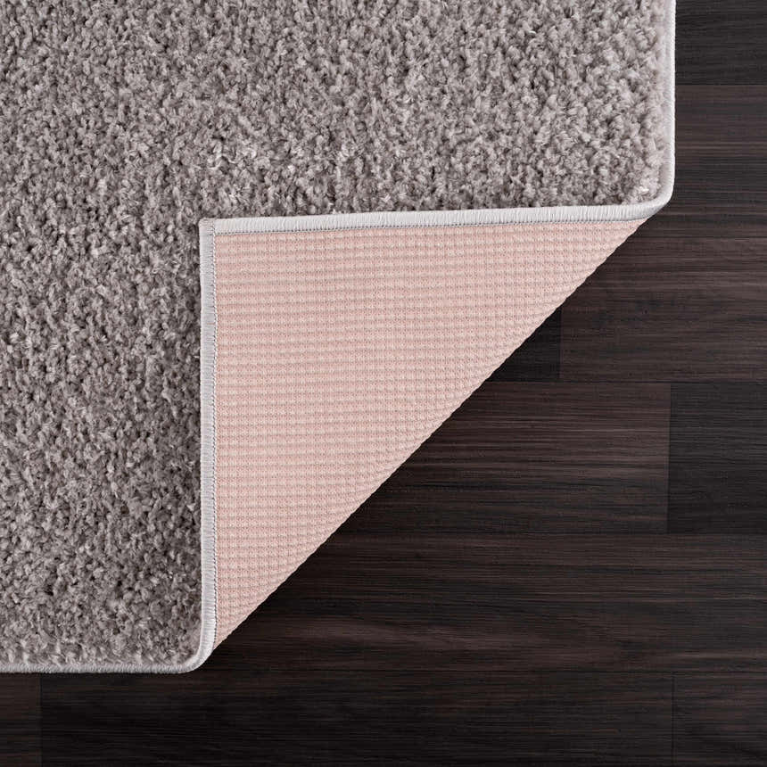 Close-up of the Judy Solid Gray Washable Shag Rug showing its soft texture and non-slip backing on dark wood floor. Back