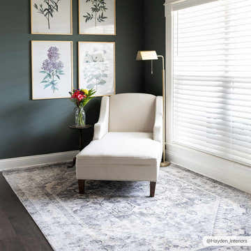 Living room scene with a gray Ailsa Area Rug, white chaise lounge, dark green walls, and botanical art prints. Roomscene-Rectangle