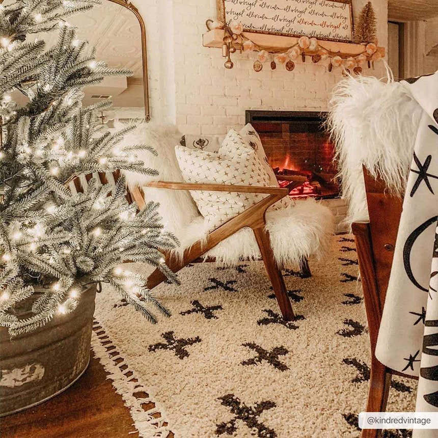 Cozy Christmas living room with Alstead Shag Area Rug, fireplace, faux fur chair, and decorated tree. Roomscene-Rectangle