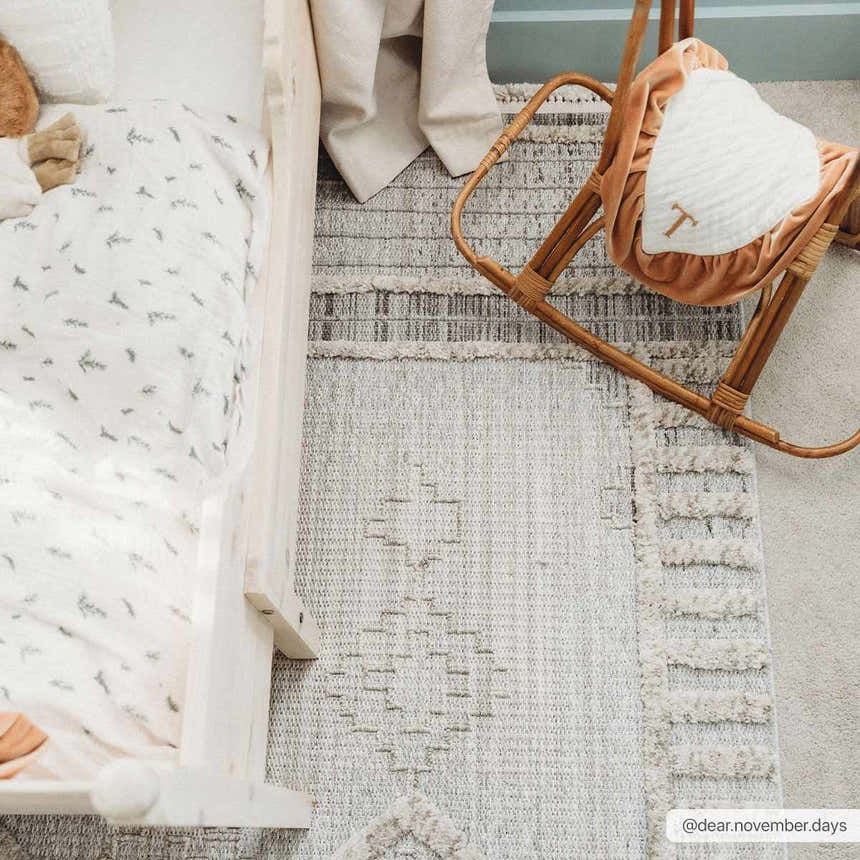 Nursery scene with a crib and rocking chair on the Amaga High-Low Rustic Rug in cream, gray, and beige tones. Roomscene-Rectangle