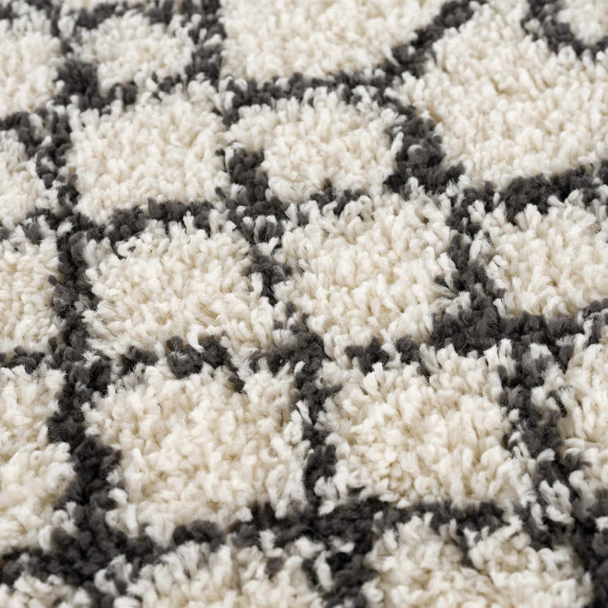 Close-up of the Muni Berber Shag Rug, featuring a charcoal geometric pattern on a light beige, high-pile shag texture. Texture