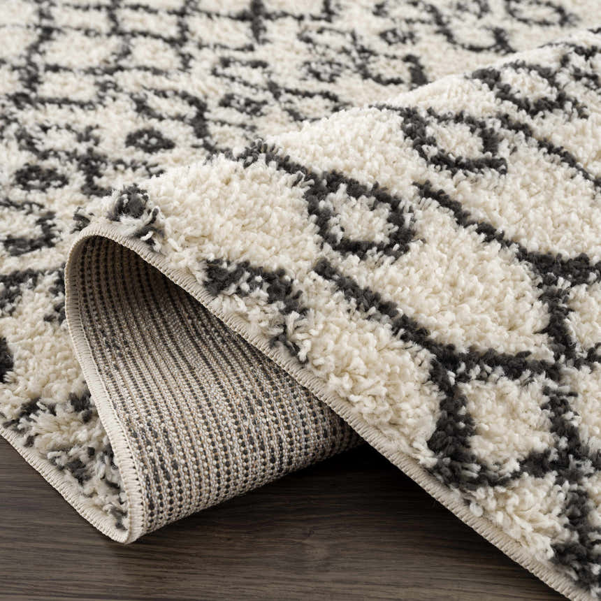 Close-up of the Muni Berber Shag Rug in charcoal and light beige, showing the shag texture and Moroccan-inspired pattern. Fold