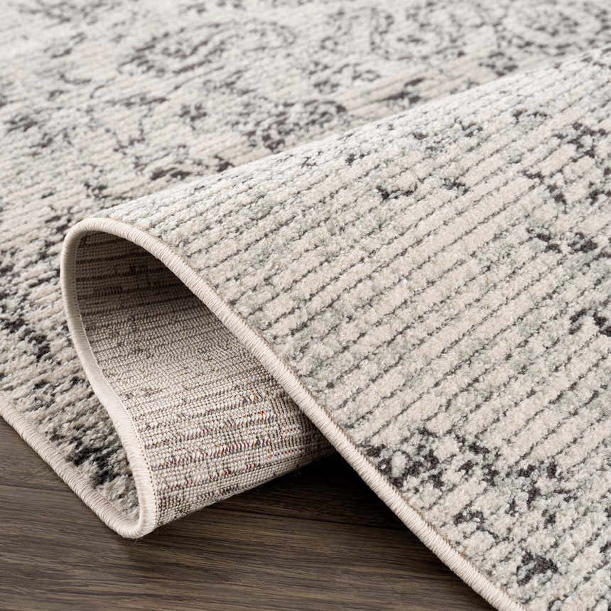 Close-up of the Paicines Area Rug, showcasing its charcoal and gray vintage-inspired pattern and soft, textured weave. Fold