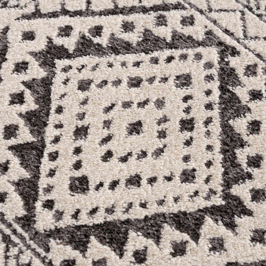 Close-up of Merriott Area Rug showing charcoal, dark brown, and light beige geometric pattern and soft texture. Texture