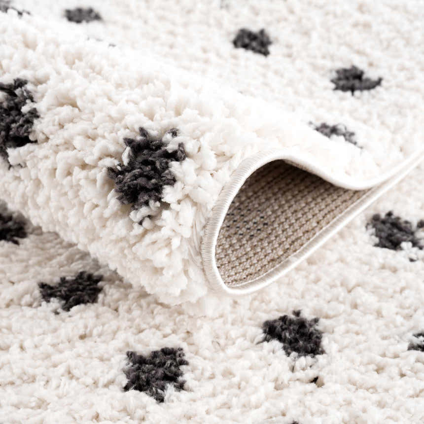 Close-up of the plush Chaia Dotted Black & White Rug showing its soft texture and black dotted pattern on a white background. Fold