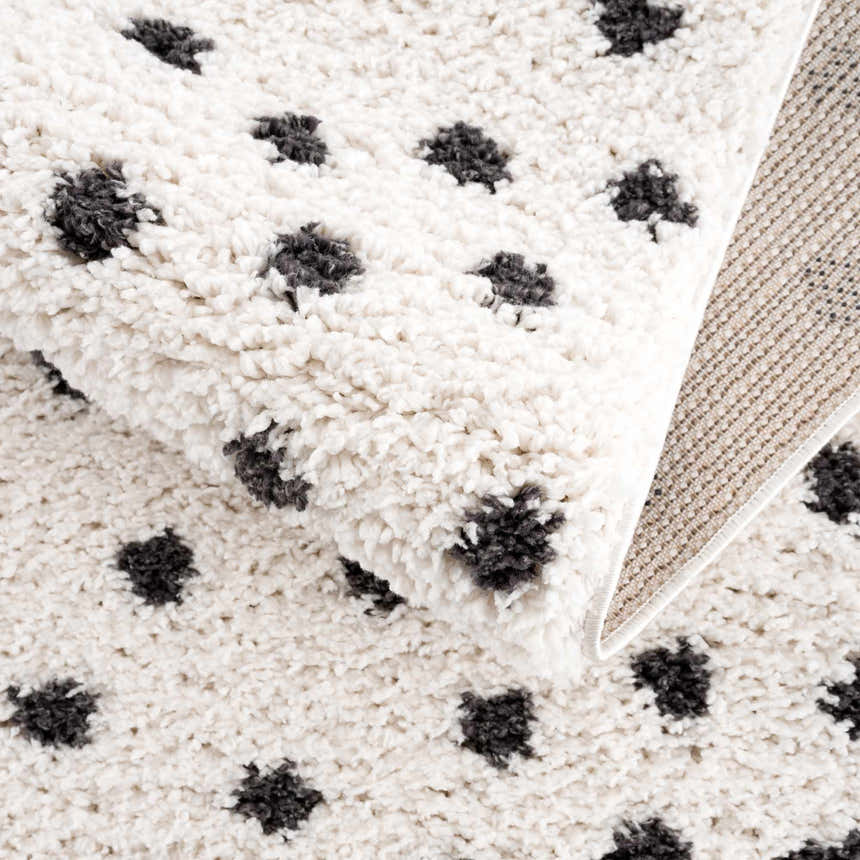 Close-up of the plush Chaia Dotted Black & White Rug, showcasing its soft texture and playful black dot pattern. Fold