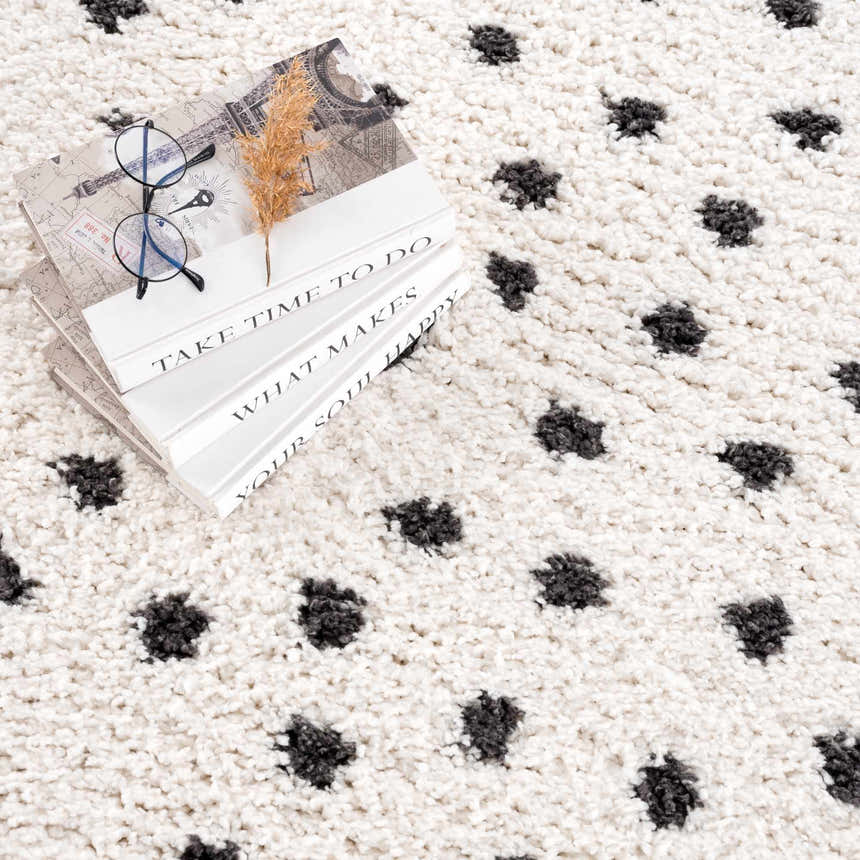 Close-up of the Chaia Dotted Black & White Plush Rug, a shag rug with a black dotted pattern on a soft, white textured background. Styleshot