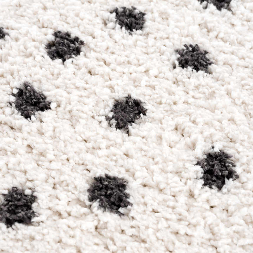 Close-up of the Chaia Dotted Black & White Plush Rug, showing its soft, shag texture and black polka dot pattern. Texture
