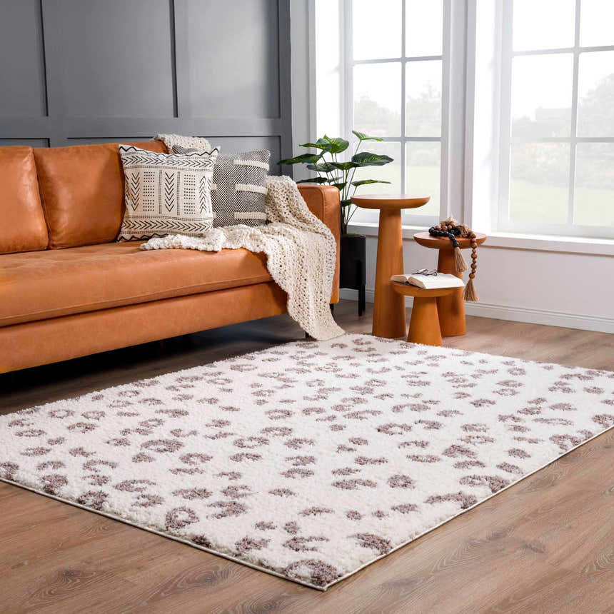 Living room scene with a Zhen Pink Spots Leopard Rug, tan leather sofa, and wood accents. Roomscene-Rectangle