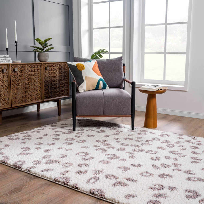 Living room scene with a Zhen Pink Spots Leopard Rug, gray chair, wood cabinet, and natural light. Roomscene-Rectangle