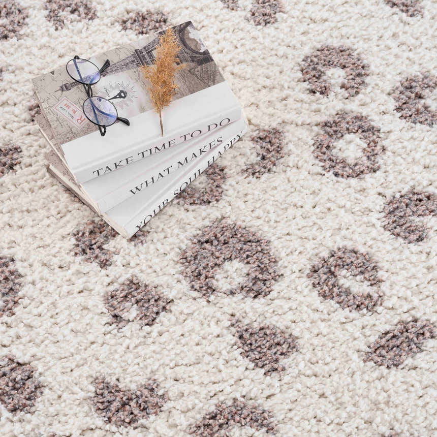 Close-up of the Zhen Pink Spots Leopard Rug, a shag rug with a brown and pink animal print on an off-white background. Styleshot