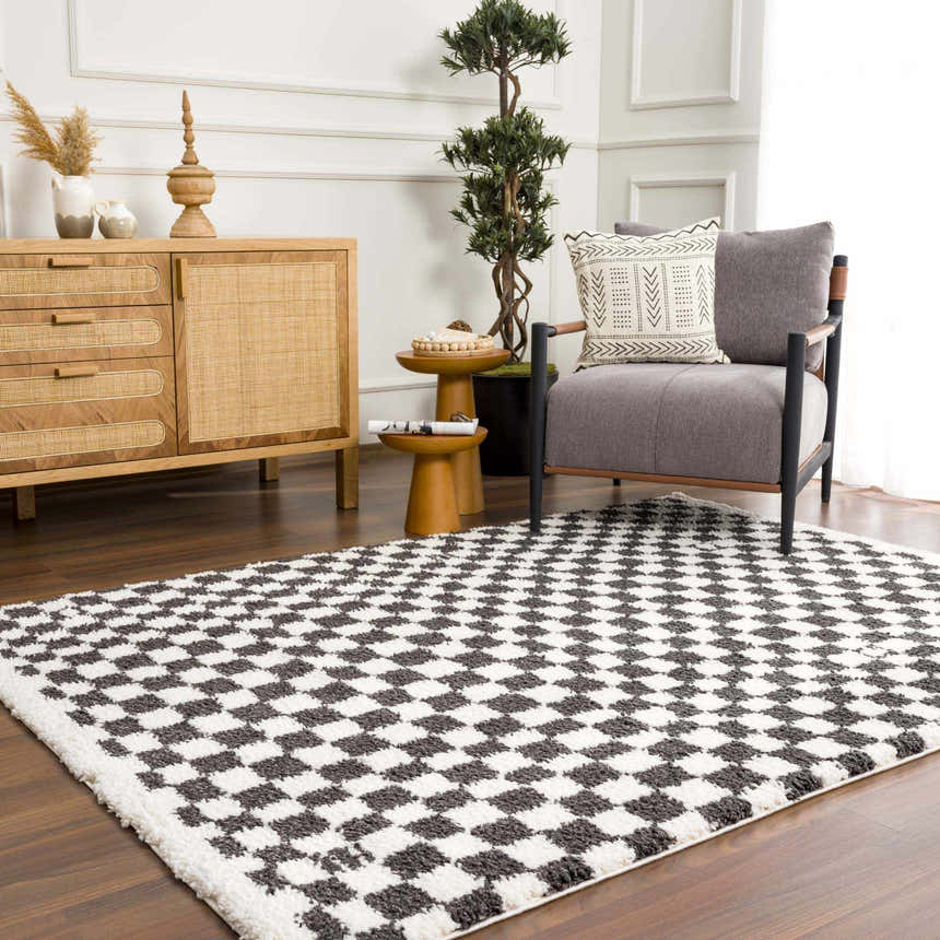 Living room scene with a Kieu Black & White Checkered Shag Rug, gray chair, and wood cabinet. Modern bohemian style. Roomscene-Rectangle