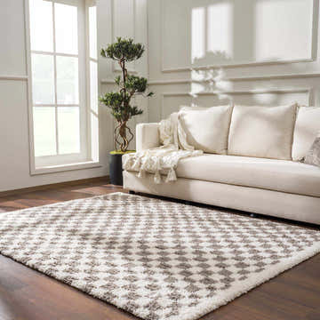 Living room scene with a Kieu Taupe Checkered Plush Rug, beige sofa, and a potted tree near a window. Roomscene-Rectangle