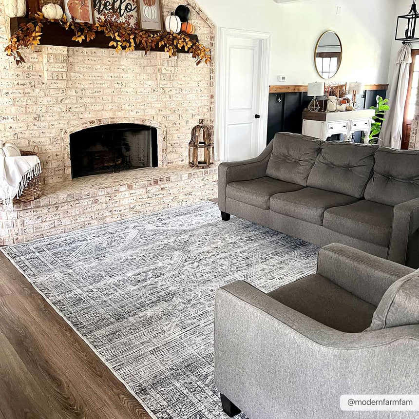 Farmhouse living room with gray sofa and Barny Gray Blue Washable Rug on wood floor near brick fireplace. Roomscene-Rectangle