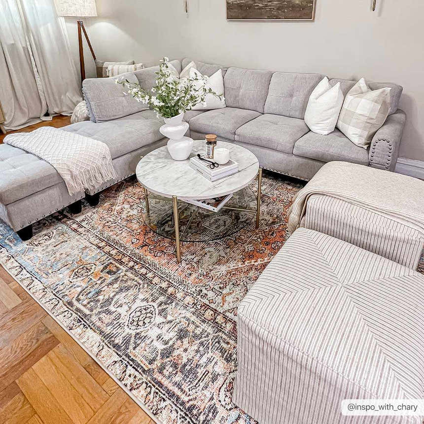 Living room scene with gray sectional, marble coffee table, and Beck Peach Washable Area Rug adding warmth and traditional style. Roomscene-Rectangle